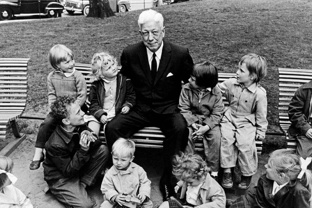 Maurice Pate, prvi izvršni direktor UNICEF-a, v Stockholmu sedi na klopi v parku, obkrožen z otroki
