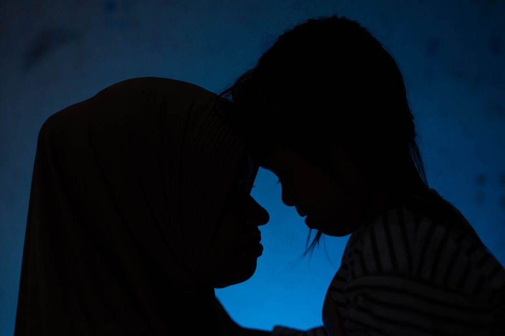 Hani (ime spremenjeno) in njena hči Kusuma, 8 let, počivata z glavama druga na drugi v svojem domu v Klatenu.