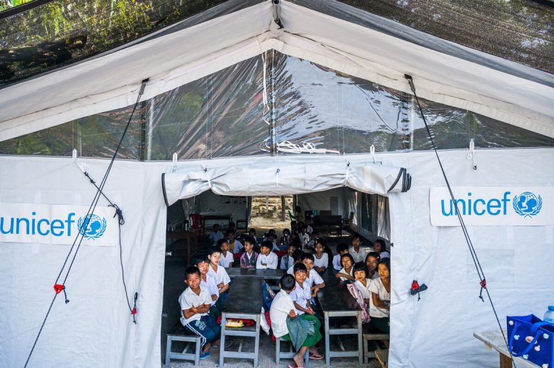 Skupina osnovnošolcev se uči v šolskem šotoru, ki ga podpira UNICEF. Mjanmar. 