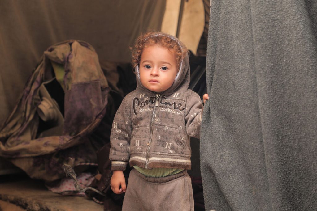 Deček stoji v šotoru.