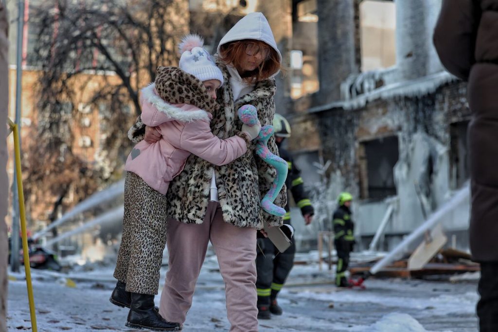 Mati nosi svojega otroka v hudi zimi v Ukrajini.