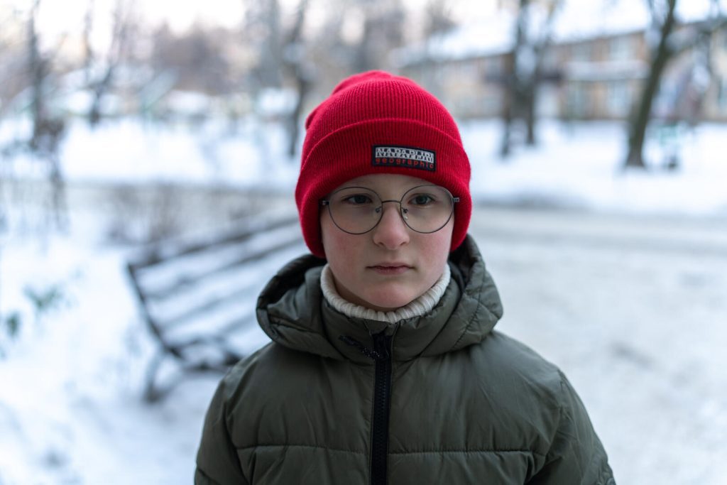 8-letni Yehor iz Ukrajine stoji pred svojo stanovanjsko stavbo.