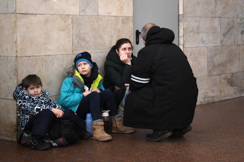 Oče, mama in dva otroka sedijo na tleh postaje podzemne železnice