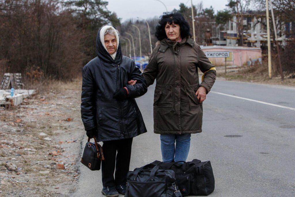 Dve gospe s prtljago, ki se držita za roke.