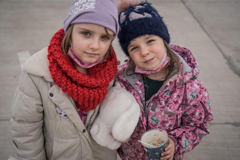 Dve deklici; ena v roki drži igračo, druga lonček.