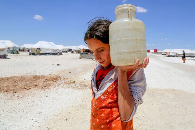 Deklica, ki na rami nosi posodo z vodo.