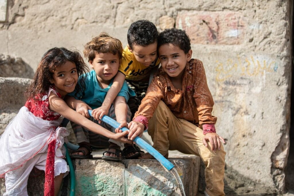 Veseli otroci črpajo čisto pitno vodo.