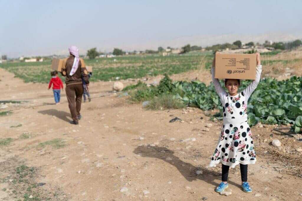 Deklica nad glavo drži UNICEF-ov paket