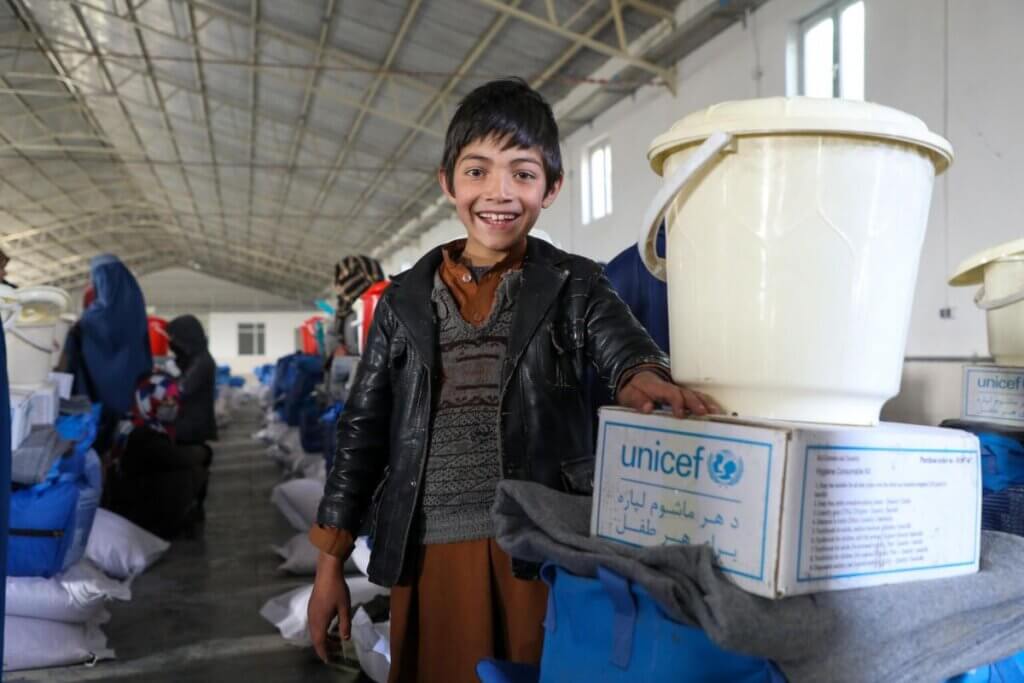 Vesel deček stoji ob UNICEF-ovi zimski opremi