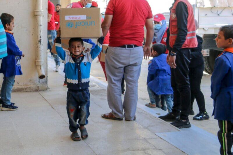 Vesel deček nad glavo nese UNICEF-ov paket