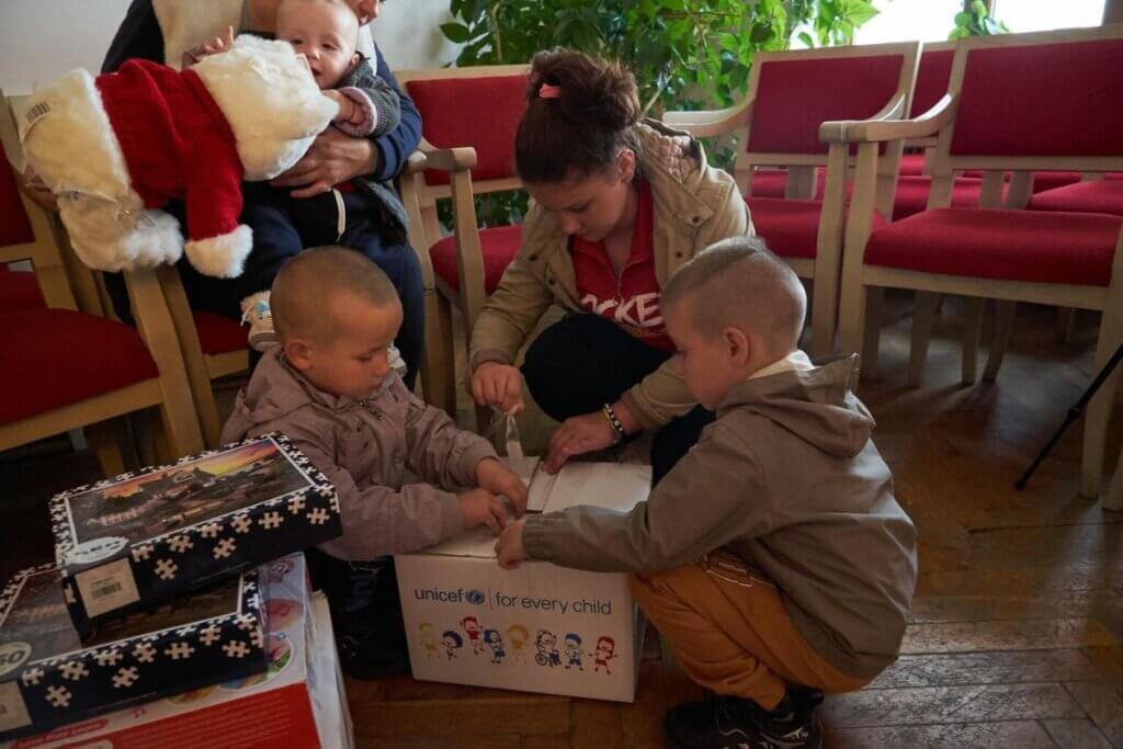 Otroci odpirajo UNICEF-ov paket zimske opreme