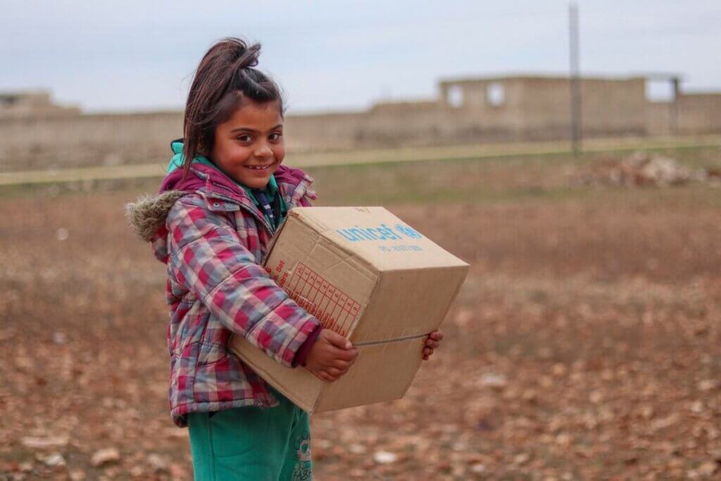 Vesela deklica drži UNICEF-ov paket