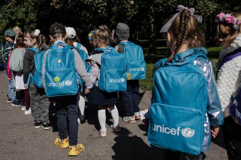 Skupina otrok z modrimi nahrbtniki, na katerih je napis UNICEF.