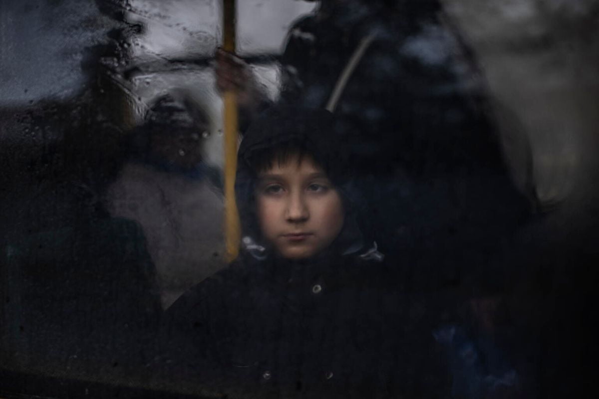 Žalosten deček gleda skozi okno avtobusa.