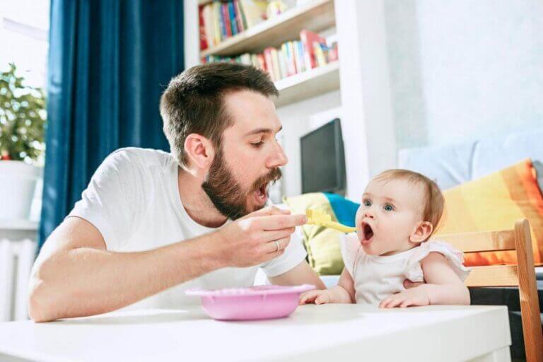 Oče hrani svojo hčerko s hrano na žličko