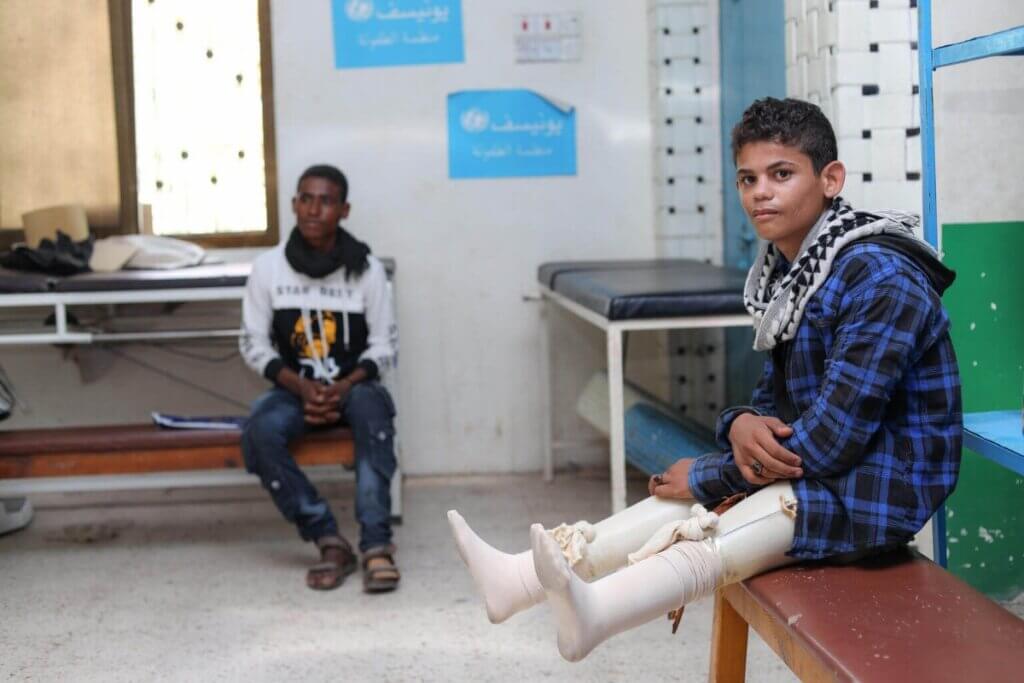 Deček z umetnimi udi sedi v v protetičnem centru v Adnu v Jemnu.