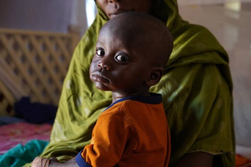 Otrok čaka na pregled v prehranskem centru v Abushoku v Sudanu.