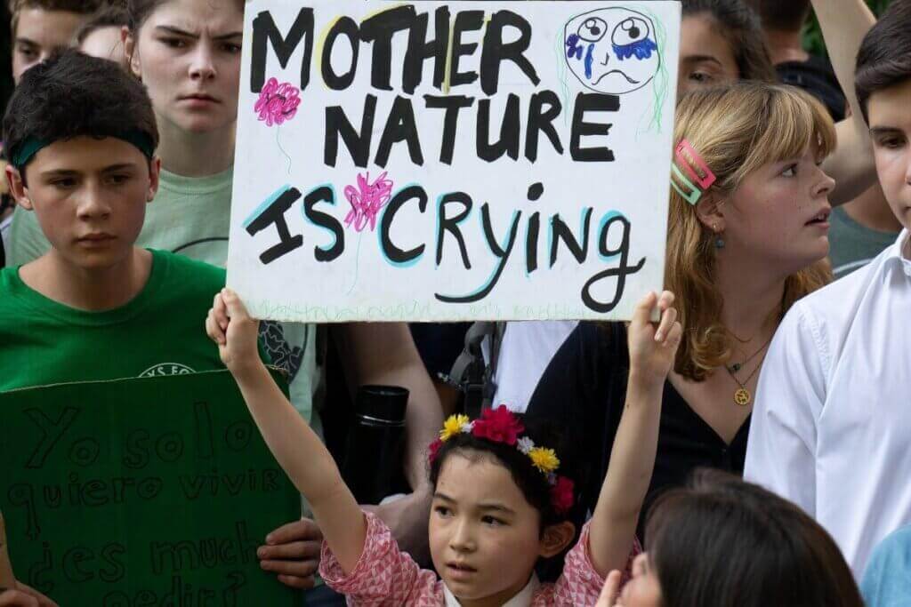 Deklica s plakatom z napisom "Mati Zemlja joče."