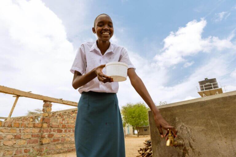 Sharlyne iz Kenije ob vodnem viru, ki ga je zagotovil UNICEF.