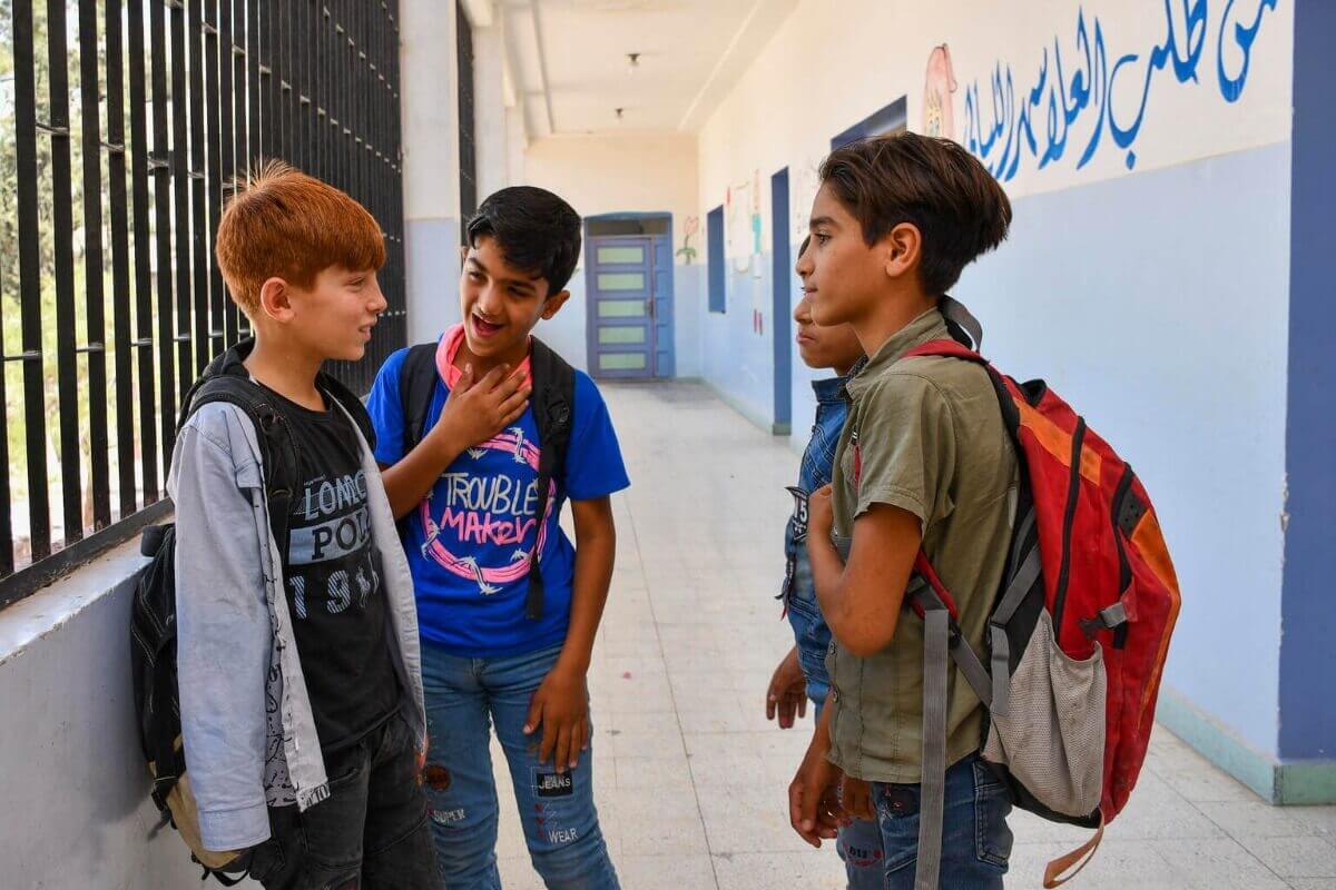 Abdulrahman klepeta s svojimi sošolci na hodniku svoje šole.