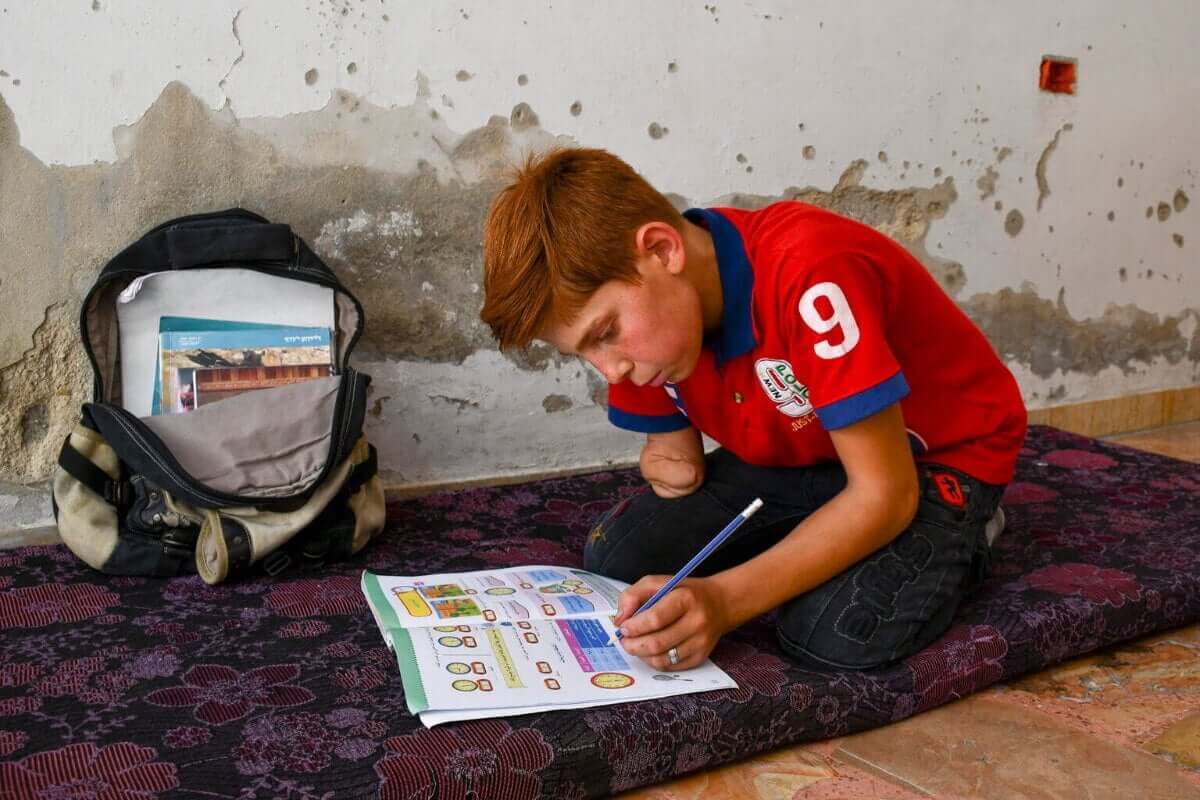 12-letni Abdulrahman doma piše domačo nalogo.