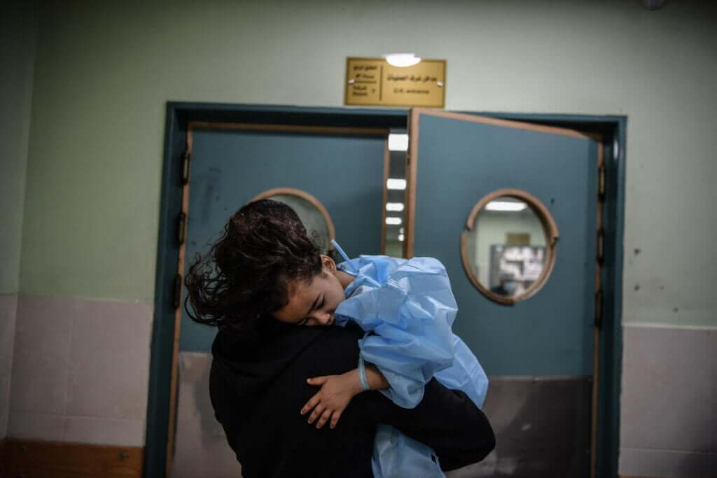Težje poškodovano deklico, ki jo čaka amputacija noge, v eni izmed redkih še delujočih bolnišnic v Gazi spremlja oče.