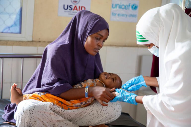 Otroku s kolero zdravstveni delavec daje injekcijo.