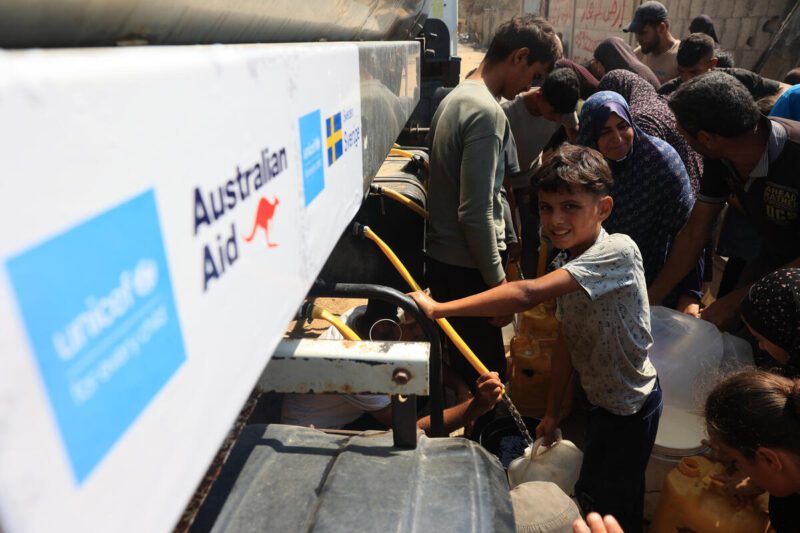 Otroci in njihove družine nosijo vodo iz tovornjaka za vodo, ki ga podpira UNICEF, v Deir al-Balahu na območju Gaze.