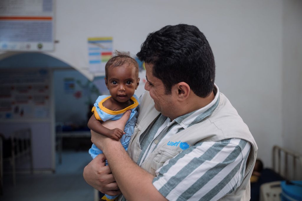 Senan Alajel, vodja programa za prehrano pri UNICEF-u, držo otroka, sprejetega v stabilizacijski center v Port Sudanu, ki ga podpira UNICEF.