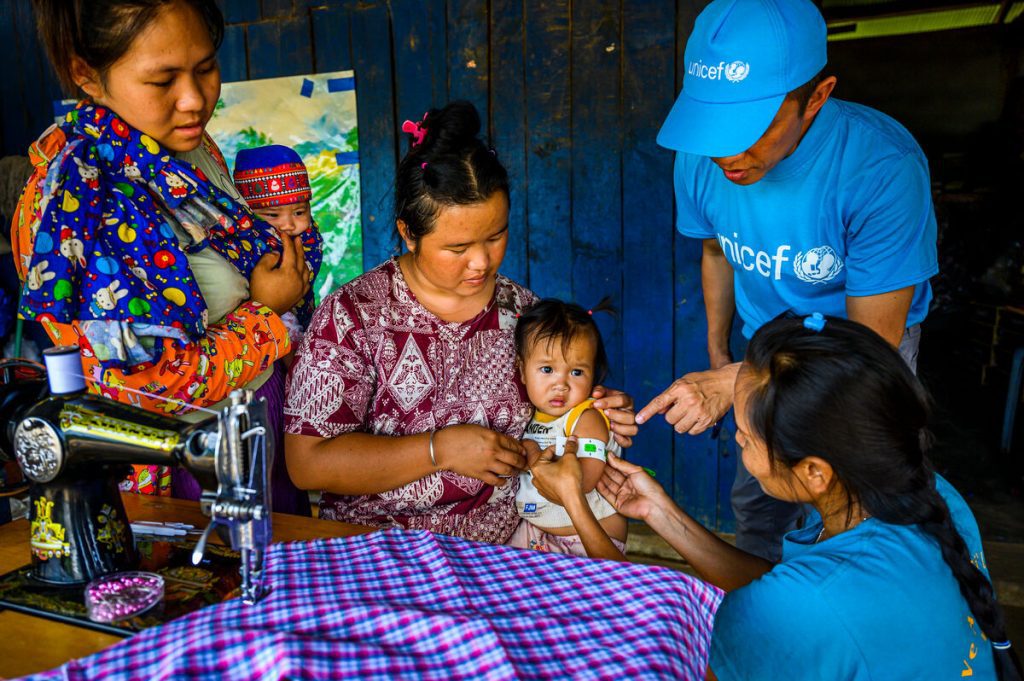 Zdravstveni delavec v Mjanmaru pregleduje otroka zar podhranjenost.