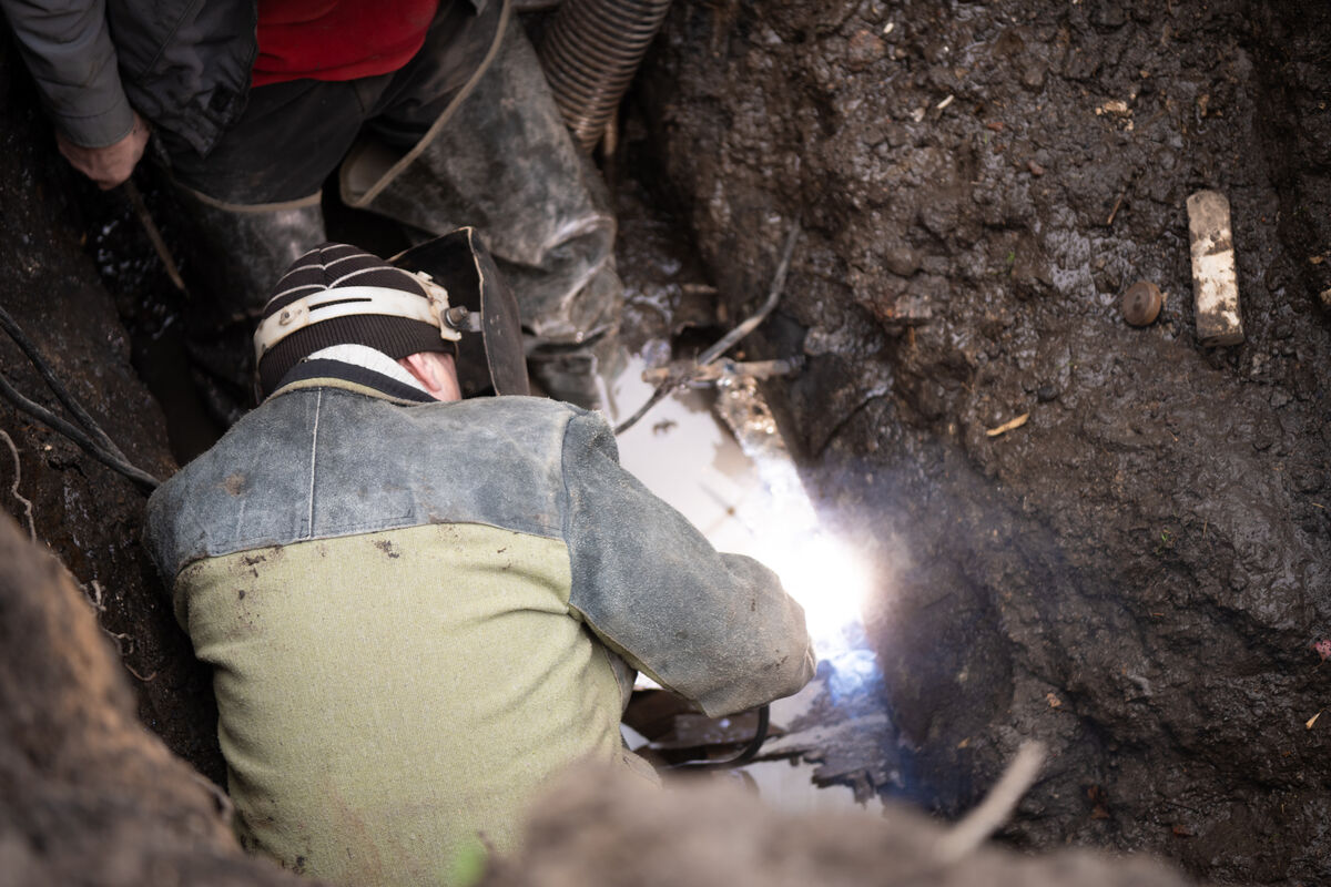 Vzdrževalec iz vodovodnega podjetja Kramatorsk vari poškodovano cev globoko pod zemljo.
