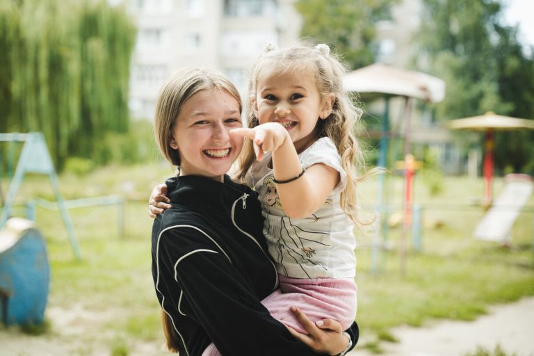 16-letna Katya drži svojo mlajšo sestro Masho, staro 4 leta, na igrišču v njihovi soseski v Ukrajini.