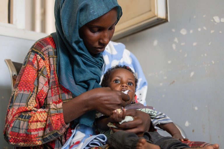 Mama Naba hrani svojega 7-mesečnega sina Adnana s terapevtsko hrano v zdravstvenem centru Eid Hussein v sudanski zvezni državi Kartum.