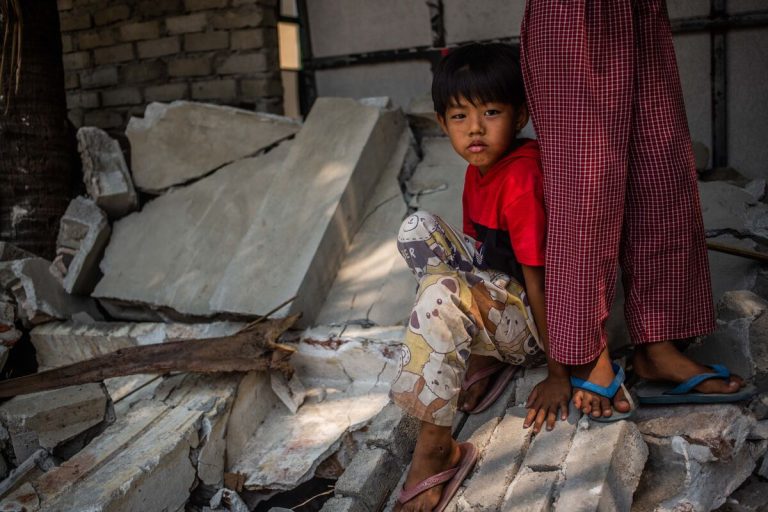 Deček sedi na delu porušenega zidu skupnostne dvorane Aye Thukha v okrožju Mahar Aung Myay v Mandalaju, Mjanmar.