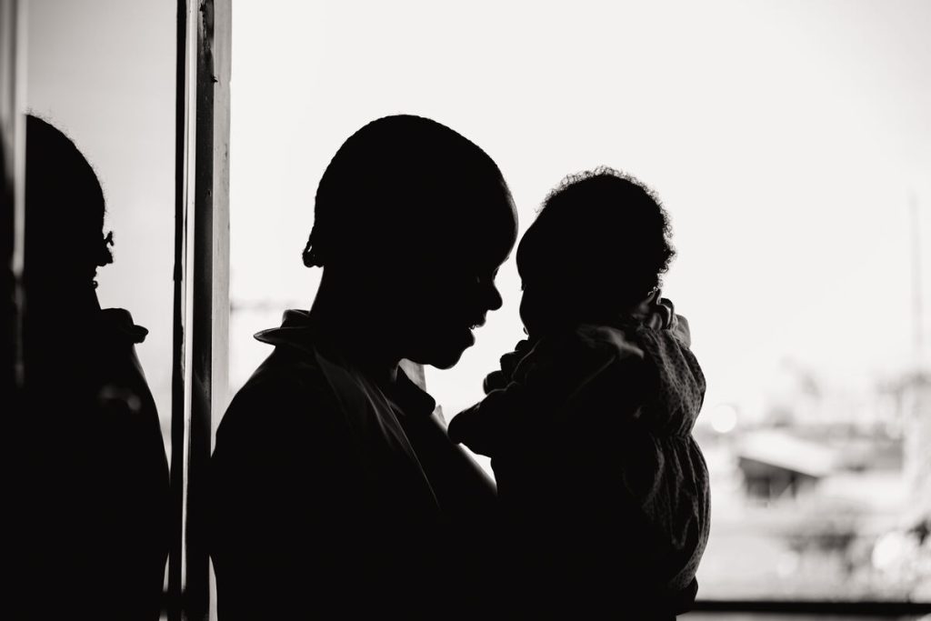 Sephora*, 18-letna mati dveh otrok, drži svojo hčerko v kliniki Karibuni wa Mama, DR Kongo.