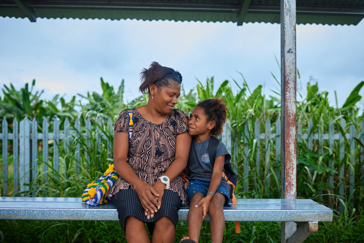 Mati in hči sedita obrnjena druga k drugi in se smejita.