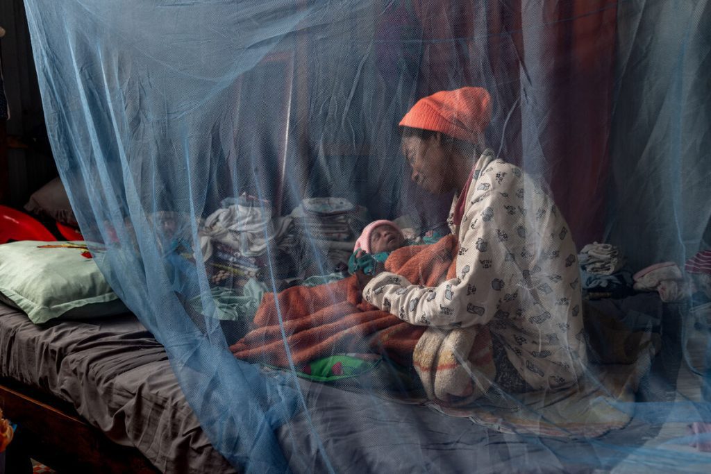 Mati pokriva otroka z mrežo proti komarjem.