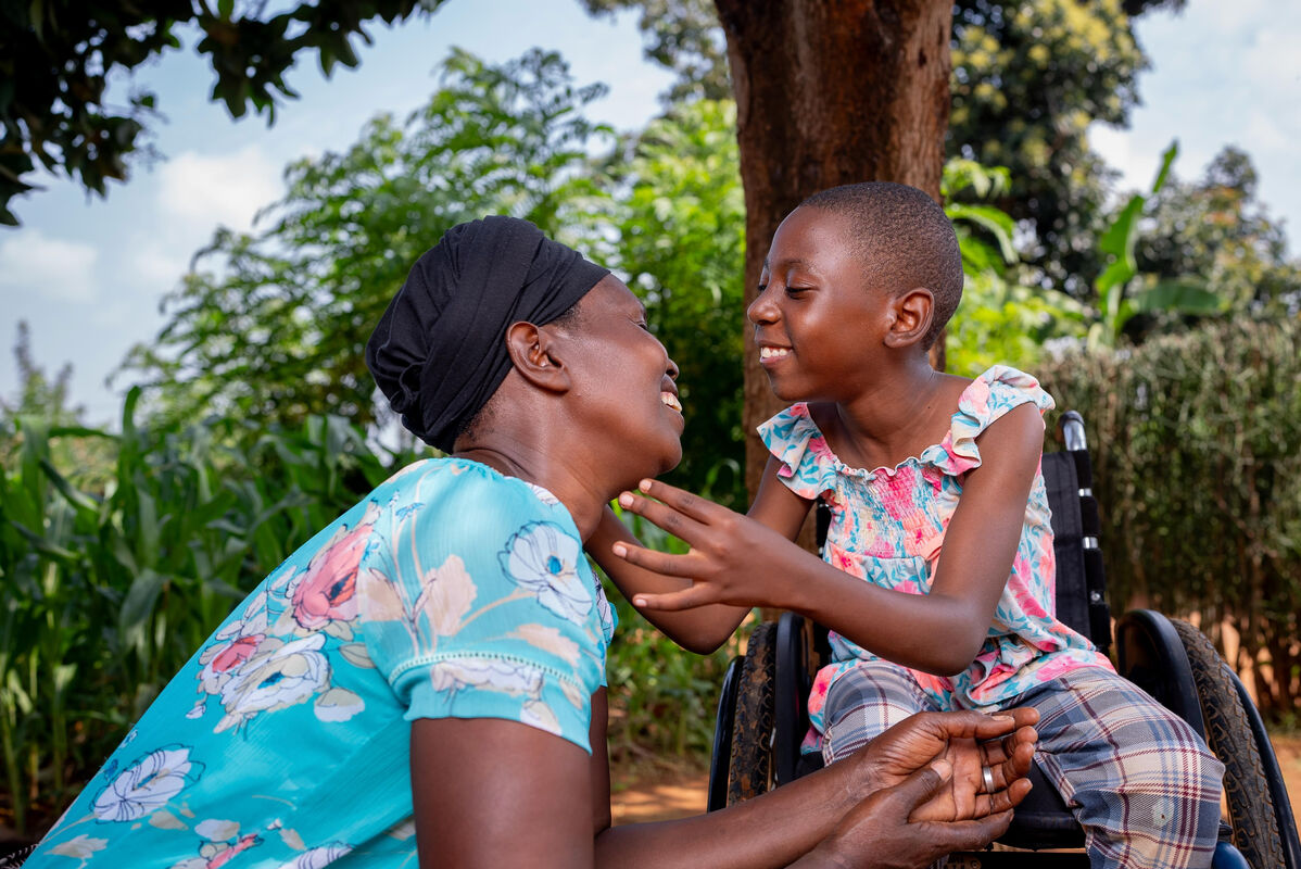 Mati in otrok se nagneta k objemu z nasmehom na obrazu.