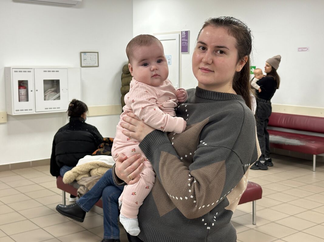 Mati v zdravstvenem centru drži svojo dojenčico in z njo pozira kameri.