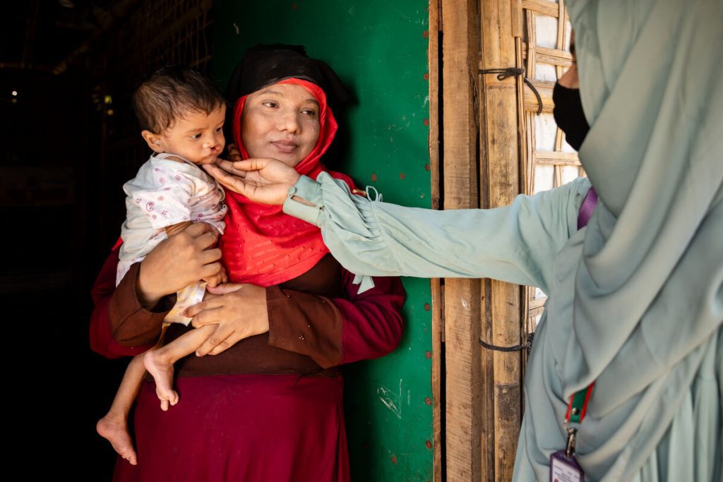 Prostovoljka za prehrano v skupnosti Rohingya, Taslima, na obisku 25-letne Rashide, da bi ji v njihovem zatočišču v begunskih taboriščih Rohingya v Cox’s Bazarju v Bangladešu ponudila svetovanje o prehrani in ocenila prehranski status njene 8-mesečne hčerke Noor.