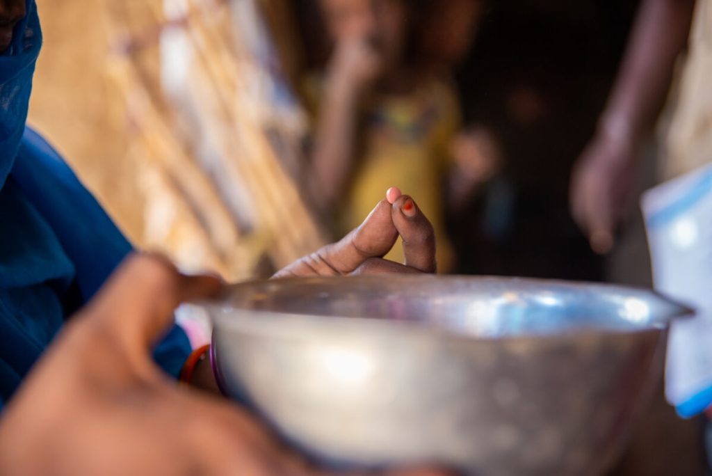 Nosečnica Umm Ali se pripravlja na jemanje tablet z železom, v okviru kampanje za prehrano, ki jo UNICEF podpira od vrat do vrat v naselju Aroma v zvezni državi Kassala. Na fotografiji je tableta in skleda vode.