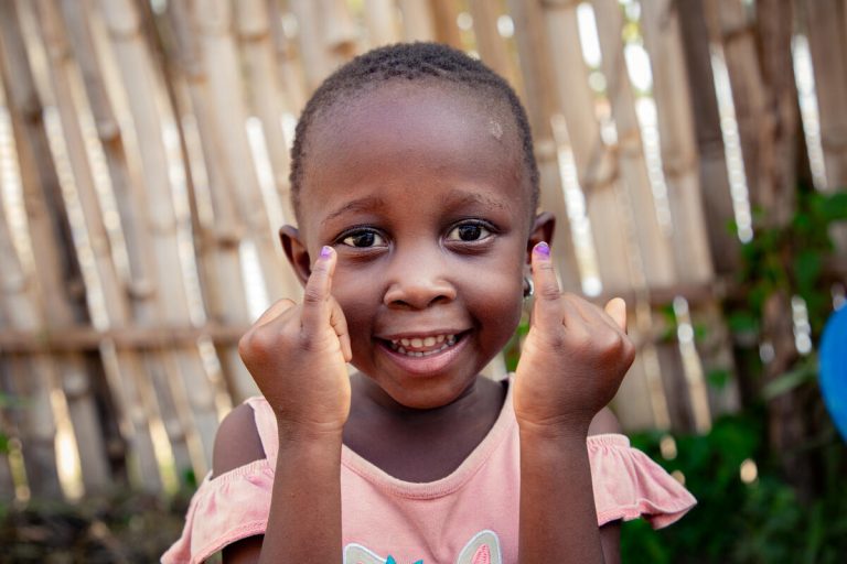 4-letna Davina iz DR Konga kaže pobarvana prsta – označba nakazuje, da je prejela cepivo proti otroški paralizi.