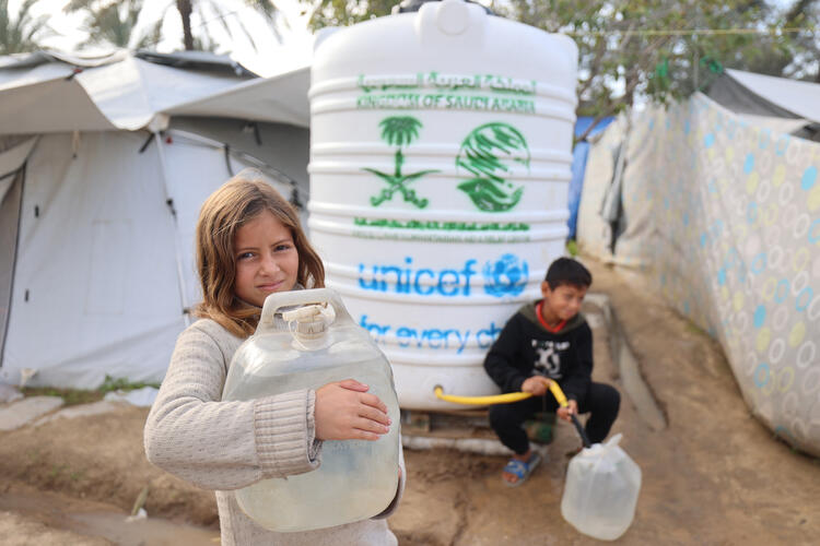 Deklica in deček iz UNICEF-ovega vodnega vira nabirata čisto pitno vodo. Gaza.