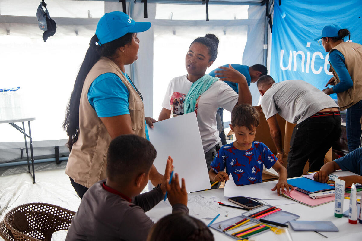16-letna Gabriela iz Venezuele v UNICEF-ovem varnem prostoru govori z UNICEF-ovo prostovoljko.