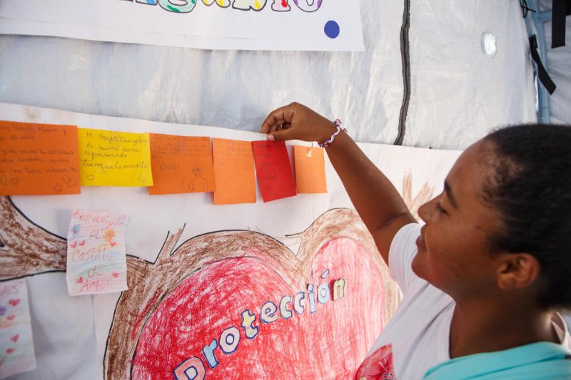 16-letna Gabriela iz Venezuele v UNICEF-ovem varnem prostoru obeša risbe in kartice s pozitivnimi mislimi.