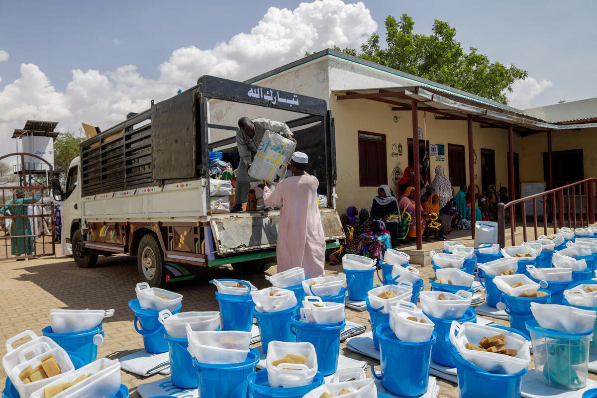 Prostovoljci raztovarjajo pomoč za oskrbo z vodo, sanitarne storitve in higieno, ki je bila nabavljena s podporo Sudanskega humanitarnega sklada.