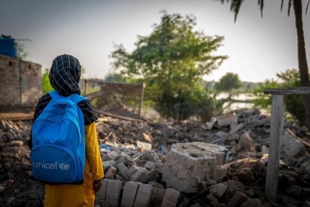 9-letna Fatima iz Pakistana stoji pred ruševinami svojega doma, ki so ga uničile monsunske poplave. S pomočjo UNICEF-a lahko sedaj ponovno obiskuje pouk v varnem okolju in ima dostop do psihosocialne podpore.