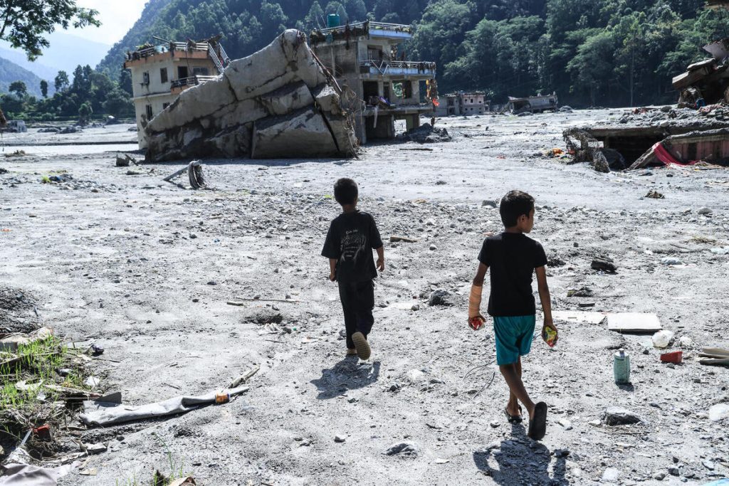 Otroka iz Nuvakota v Nepalu stojita na območju, kjer je pred poplavami stala njuna šola.