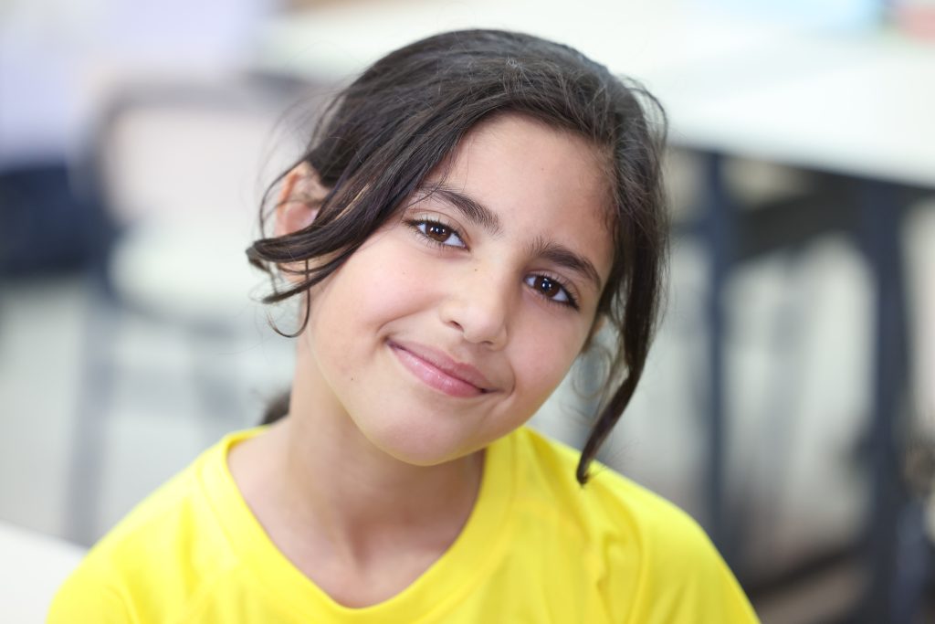Deklica, udeleženka UNICEF-ovega poletnega programa v Gazi, se nasmiha v objektiv.
