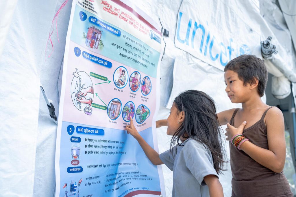 Deklici v zdravstvenem šotoru, ki ga podpira UNICEF v okrožju Nuvakot, bereta gradivo z napotki za lažje soočanje s strahom in stisko po nedavnih poplavah.